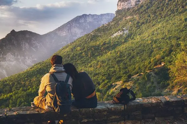 Lovers taking a rest and seating at the rock facing the mountain and enjoying the view