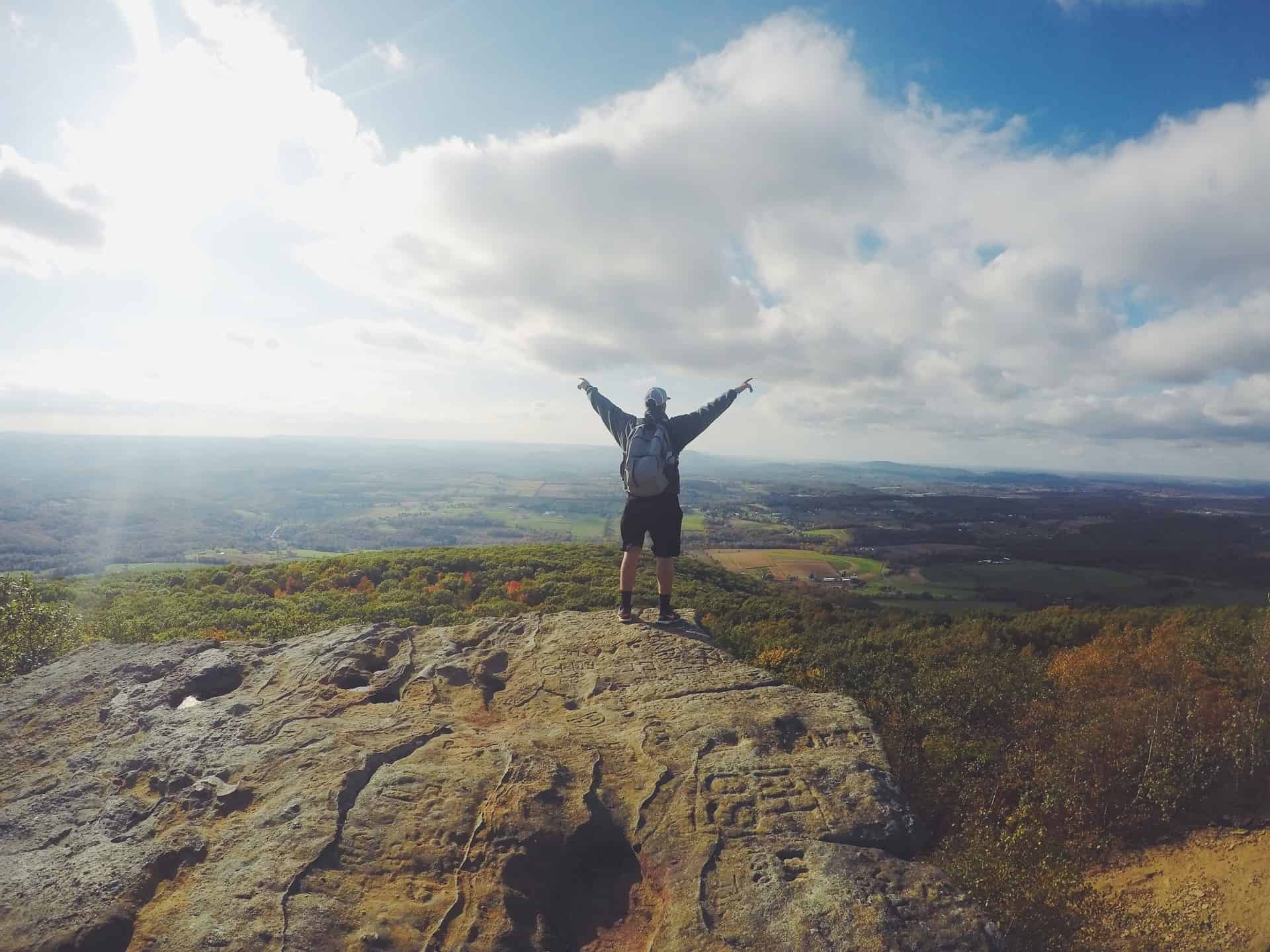 Man raising his both hands as he reach the top of the mountain