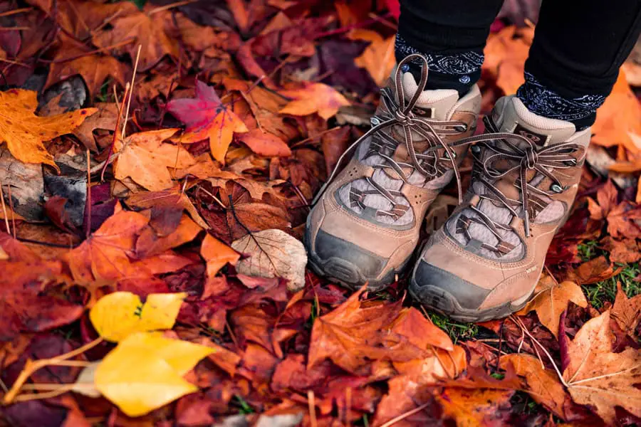 Hiking boots step on the red autumn leaves